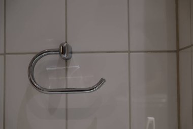 Güzel, parlak tuvalet kağıdı tutacağı beyaz seramik fayanslarla kaplı duvara asılı. Temiz ve modern banyo aksesuarları ve parlak bir tasarımı var.