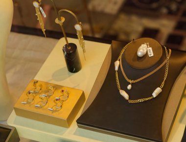 Zarif bir inci gerdanlık ve küpeler, taşlarla süslenmiş altın yüzükler ve küçük incilerle sarkıtılmış küpeler içeren bir mücevher mağazası..