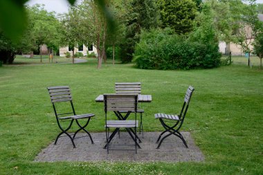 Bereketli çimlerle çevrili iyi korunan bir çimenlik, açık hava masası ve çalılar ve ağaçlar arasında kurulmuş metal ve ahşaptan yapılmış dört sandalyenin yer aldığı küçük taşla kaplı bir alanı kaplar..