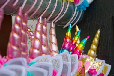 Canlı tek boynuzlu at boynuzu ve parlak kumaşlı ve parlak detaylı kedi kulaklıkları. Bir turist dükkanında sergileniyor, eğlenceli aksesuarlar ve hediyeler için mükemmel..