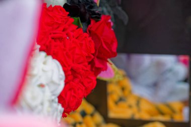 Kırmızı siyah ve beyaz tonlarda suni dekoratif çiçekler. Muhtemelen hediyelik eşyalar ya da satılığa çıkarılmış eşyalar. Ev ve hediyeler için zarif ve renkli aksanlar.