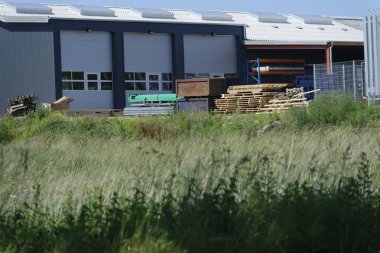 İnce çapraz çubuklu metal bir çit siyah muşamba kumaşla kaplıdır. Arka bahçenin bir bölümünü kaplayan ve tarayan, birbiri ardına birbirinin aynı birden fazla bölüm var..