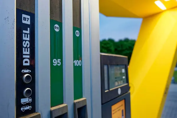 Benzin istasyonunda 95 ve 100 benzin etiketli pompalar, açık tabela ve otomatik ödeme makinesi var. Kurulum mevcut yakıt seçeneklerini ve kullanışlı self servisi yansıtıyor.