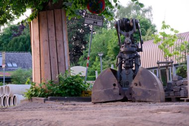 Yol kenarındaki büyük bir bloğun yanında bir kazı kovası bulunan bir inşaat alanı. Metal çitlerle ve güvenlik için diğer koruyucu bariyerlerle çevrili alana park yasağı işareti koyuldu..