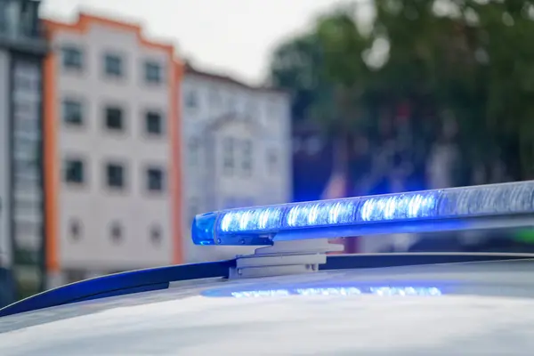 Flensburg Almanya 'sında mavi ışıklı bir Alman polis arabasının arka planında tipik evler ve güvenlik görevleri yer alıyor..