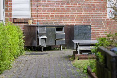 Eski paslanmaz çelik mutfak dolabı tuğla duvara dayanıyor. Yenileme, geri dönüşüm, atık imhası, sürdürülebilirlik veya gastronomi güncellemesi kavramları için ideal.