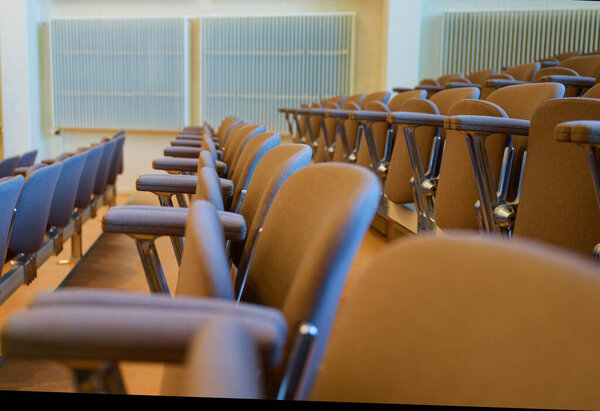 Neat rows of upholstered gray chairs fill the venue with every seat folded up. The clean aisle lines and calm light suggest a rehearsal break in a modern hall ready for the next audience.