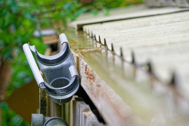 Çatı hattı boyunca drenaj sistemi parçalandı, gri plastik borular hizalanmadı ve eklem boşlukları açıldı, yağmur suyu izleri sızıntı olduğunu ve yakında onarılması gerektiğini gösteriyor.