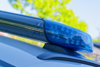 Devriye arabasındaki mavi işaret, gün ışığında bar parıldıyor, vida ve montların ayrıntıları açık, araç hala hareket halindeyken bile işaret ediyor.