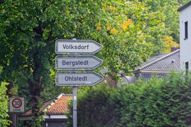 Üç yol işareti Volksdorf Bergstedt ve Ohlstedt 'i işaret ediyor. Bir bölge 30 işaret geride duruyor, alçak evler caddede bir ve iki katlı, köşe yerel ve sessiz.
