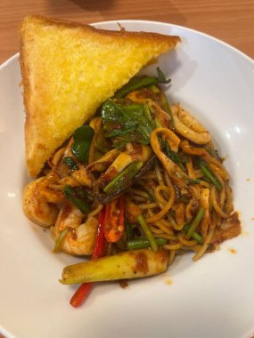 Lezzetli yemekler beyaz kasede servis edilir. İçinde karides, midye ve mürekkep balığı da dahil olmak üzere deniz mahsullü erişte var.. 