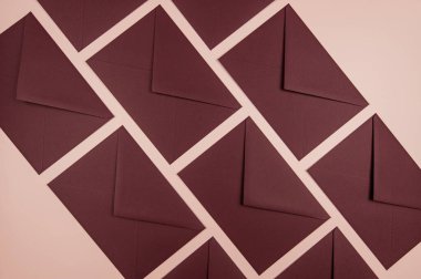 Pembe arka planda koyu kırmızı zarfların üst görüntüsü. Düz yaylan.  