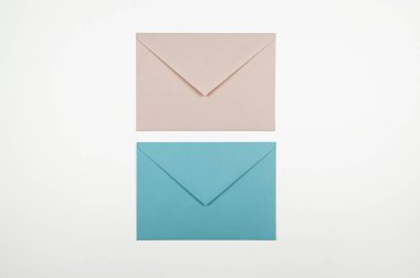 Beyaz arkaplanda mavi ve pembe zarfların üst görüntüsü. Yat yere. Boşluğu kopyala.