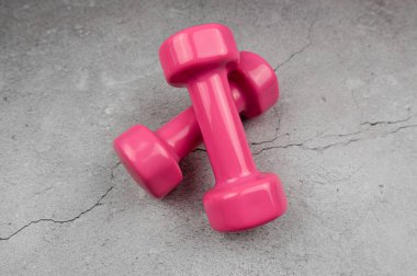 Gri beton arka planda pembe dambıllar. Fitness, spor, sağlık.