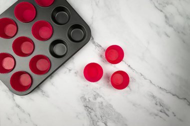 Kek tepsisinin ve beyaz mermer arka plandaki silikon kutuların en üst görüntüsü. Çörekler ve çörekler pişirme, düzleştirme, kopyalama alanı.