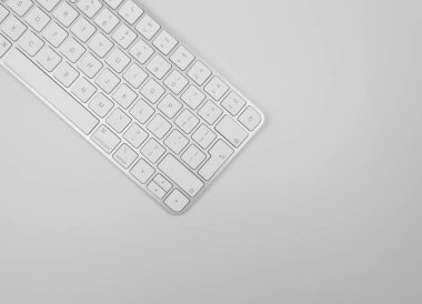 Açık gri arkaplanda beyaz klavyenin üst görünümü. Modern ofis yatağı, kopyalama alanı.