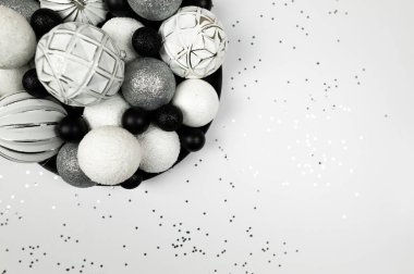 Noel kompozisyonu, köknar ağacı süslemeleri, beyaz, gümüş ve siyah takılar, beyaz arka planda gümüş yıldız konfetileri. Noel, yeni yıl, kış konsepti. Üst görünüm, düz görünüm, kopyalama alanı. 