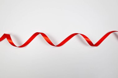 Beyaz arkaplanda kırmızı kurdelenin üst görüntüsü. Parlak rulo kumaş, ipek ve saten kumaş. Boşluğu kopyala.