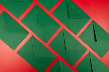 Kırmızı arkaplanda yeşil zarfların üst görüntüsü. Noel, yeni yıl kompozisyonu. Düz yatay, kopyala boşluk.