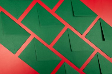 Kırmızı arkaplanda yeşil zarfların üst görüntüsü. Noel, yeni yıl kompozisyonu. Düz yatay, kopyala boşluk.