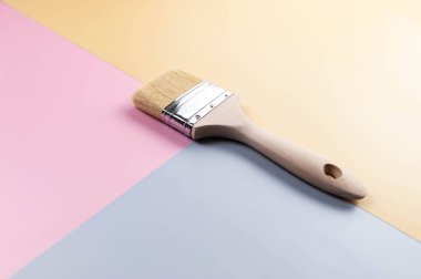 Renkli arka planda boya fırçasının üst görüntüsü. Mavi, pembe ve sarı arka plan. Renkli duvar kağıdı, düz yatak, kopyalama alanı.