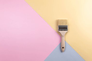 Renkli arka planda boya fırçasının üst görüntüsü. Mavi, pembe ve sarı arka plan. Renkli duvar kağıdı, düz yatak, kopyalama alanı.