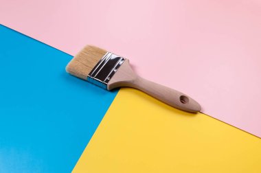 Renkli arka planda boya fırçasının üst görüntüsü. Mavi, pembe ve sarı arka plan. Renkli duvar kağıdı, düz yatak, kopyalama alanı.