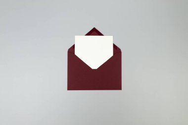 Kırmızı zarfın üst görüntüsü, gri arkaplanda beyaz kart. Yat yere. Boşluğu kopyala.