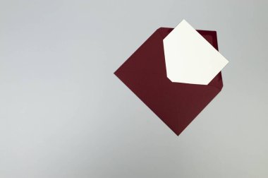 Kırmızı zarfın üst görüntüsü, gri arkaplanda beyaz kart. Yat yere. Boşluğu kopyala.