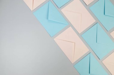 Gri arkaplanda pembe ve mavi zarfların üst görüntüsü. Renkli zarflar, duvar kağıtları, düz yatak. Boşluğu kopyala.
