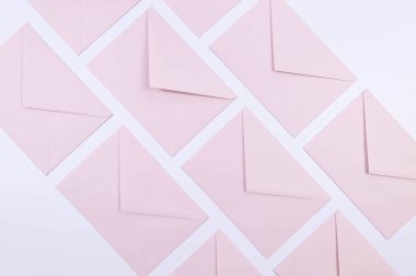Beyaz arka planda açık pembe zarfların üst görüntüsü. Yat yere. Boşluğu kopyala.