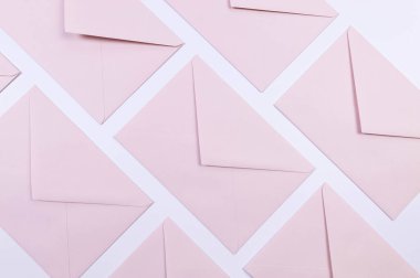 Beyaz arka planda açık pembe zarfların üst görüntüsü. Yat yere. Boşluğu kopyala.