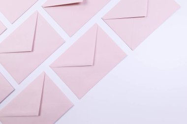 Beyaz arka planda açık pembe zarfların üst görüntüsü. Yat yere. Boşluğu kopyala.