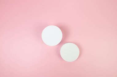 Pembe arka planda iki beyaz podyumun üst görüntüsü. Kozmetik ürün sunumu için geometrik soyut şekiller. Düz yat, boşluğu kopyala.