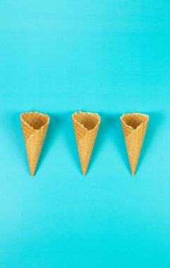 Mavi arka planda üç dondurmalı waffle külahının üst görüntüsü. Yaz duvar kağıdı, düz döşeme, kopyalama alanı.