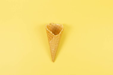 Sarı arka planda dondurmalı waffle külahının en üst görüntüsü. Yaz duvar kağıdı, düz döşeme, kopyalama alanı.