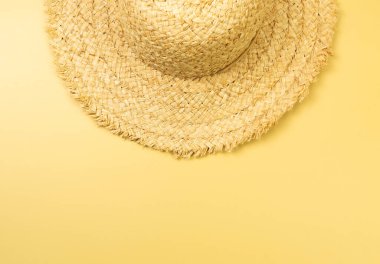 Sarı arkaplandaki hasır şapkanın üst görüntüsü. Yaz modası, tatil ve plaj duvar kâğıdı. Uzayı kopyala, düz yat.