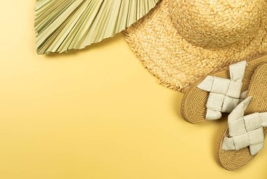 Hasır şapka, terlik ve sarı arka planda kurumuş palmiye yaprağı. Yaz modası, tatil ve plaj duvar kâğıdı. Uzayı kopyala, düz yat.