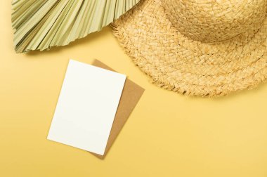 Hasır şapka, kurutulmuş palmiye yaprağı ve sarı arka planda kart. Yaz modası, tatil ve plaj duvar kâğıdı. Uzayı kopyala, düz yat.