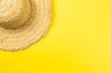 Sarı arkaplandaki hasır şapkanın üst görüntüsü. Yaz modası, tatil ve plaj duvar kâğıdı. Uzayı kopyala, düz yat.