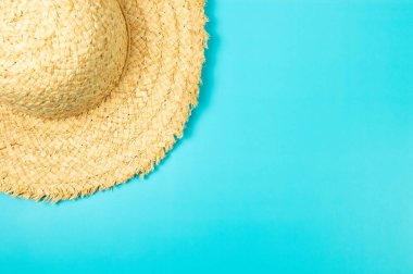 Mavi arkaplandaki hasır şapkanın üst görüntüsü. Yaz modası, tatil ve plaj duvar kâğıdı. Uzayı kopyala, düz yat.