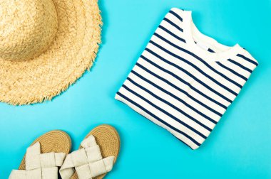 Hasır şapka, terlik ve mavi arka planda çizgili tişört manzarası. Yaz modası, tatil ve plaj duvar kâğıdı. Uzayı kopyala, düz yat.