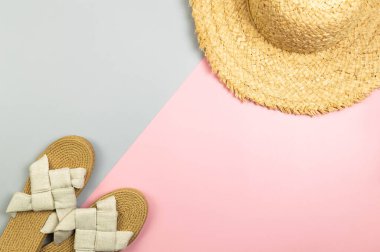 Renkli arka planda hasır şapka ve terliklerin üst görüntüsü. Yaz modası, tatil ve plaj duvar kâğıdı. Uzayı kopyala, düz yat.