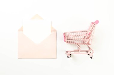 Beyaz arka planda pembe alışveriş arabasının üst görüntüsü. Pembe zarf, beyaz kart, posta. Yaratıcı alışveriş duvar kâğıdı, satış. Uzayı kopyala, düz yat.
