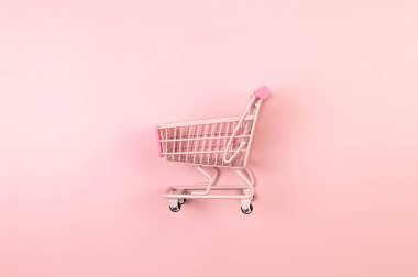 Pembe arka planda pembe alışveriş arabasının manzarası. Yaratıcı alışveriş duvar kâğıdı, satış. Uzayı kopyala, düz yat.