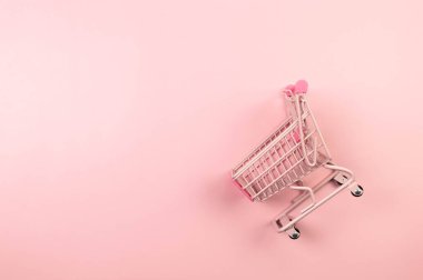 Pembe arka planda pembe alışveriş arabasının manzarası. Yaratıcı alışveriş duvar kâğıdı, satış. Uzayı kopyala, düz yat.