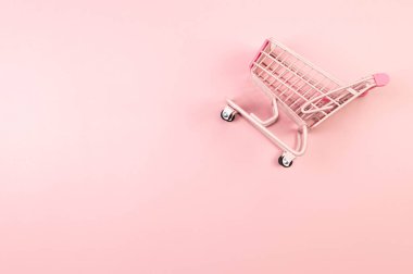Pembe arka planda pembe alışveriş arabasının manzarası. Yaratıcı alışveriş duvar kâğıdı, satış. Uzayı kopyala, düz yat.