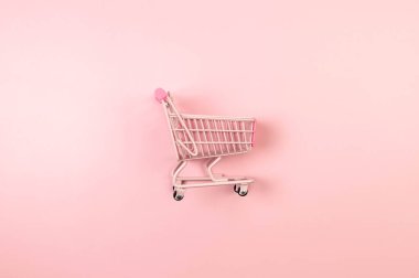 Pembe arka planda pembe alışveriş arabasının manzarası. Yaratıcı alışveriş duvar kâğıdı, satış. Uzayı kopyala, düz yat.
