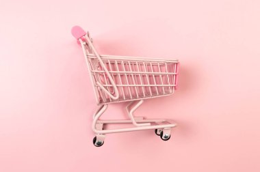Pembe arka planda pembe alışveriş arabasının manzarası. Yaratıcı alışveriş duvar kâğıdı, satış. Uzayı kopyala, düz yat.