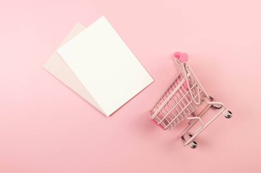 Pembe arka planda pembe alışveriş arabasının manzarası. Yaratıcı duvar kâğıdı, beyaz kart, indirim. Uzayı kopyala, düz yat.